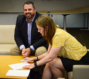 man and woman signing papers on a coffee table